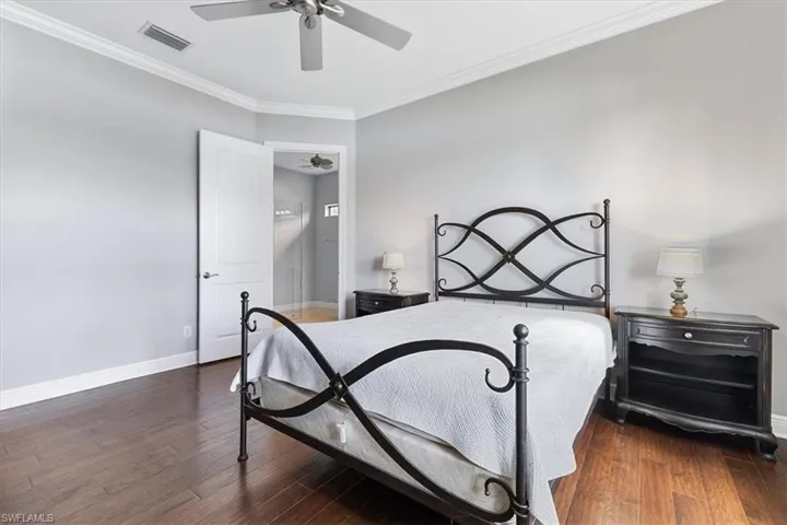 Bedroom featuring baseboards, ornamental molding, wood finished floors, and ceiling fan
