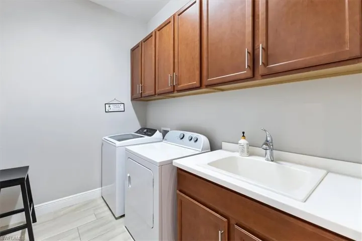 Laundry room with separate washer and dryer, cabinet space, and baseboards