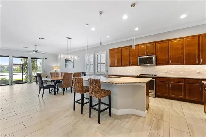 Kitchen with stainless steel appliances, a sink, decorative backsplash, light stone countertops, and pendant lighting