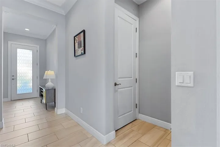 Corridor with baseboards, crown molding, and wood tiled floors