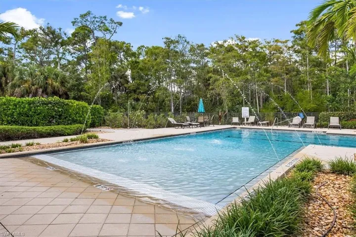 Community pool featuring fence, a patio, and view of scattered trees