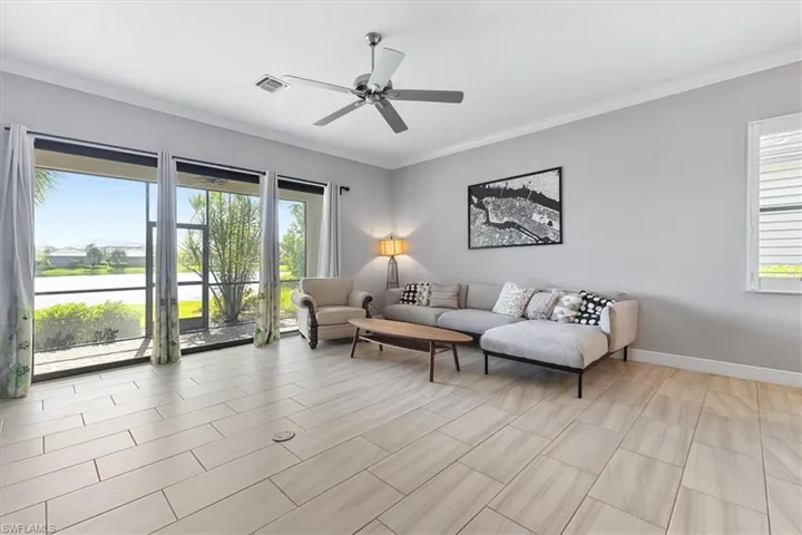 Living room with healthy amount of natural light, a ceiling fan, ornamental molding, and baseboards