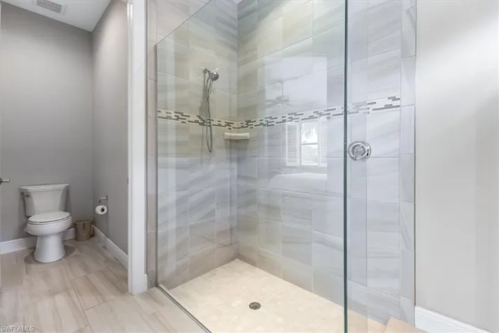 Bathroom with a stall shower, toilet, and baseboards
