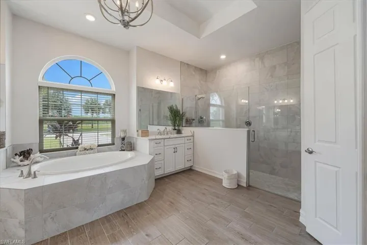 Bathroom with healthy amount of natural light, vanity, a garden tub, a stall shower, and recessed lighting
