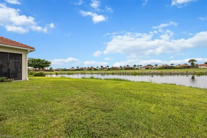 View of green lawn with a water view and a sunroom