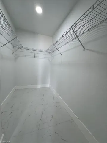 Walk in closet with light marble finish flooring