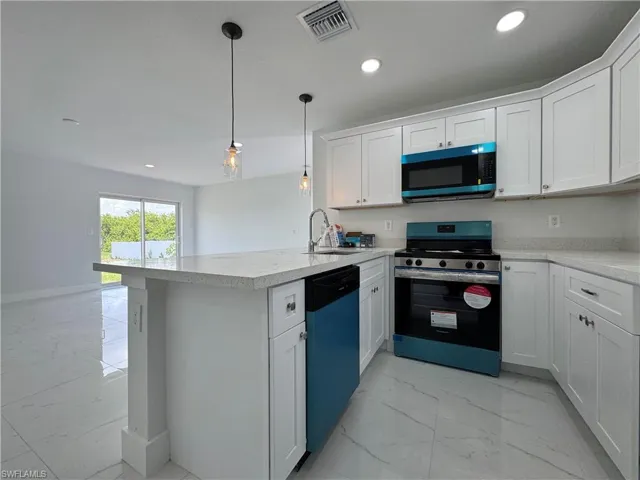 Kitchen featuring stainless steel appliances, light marble finish floors, a peninsula, and white cabinets