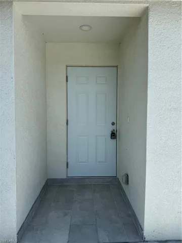 Doorway to property featuring stucco siding