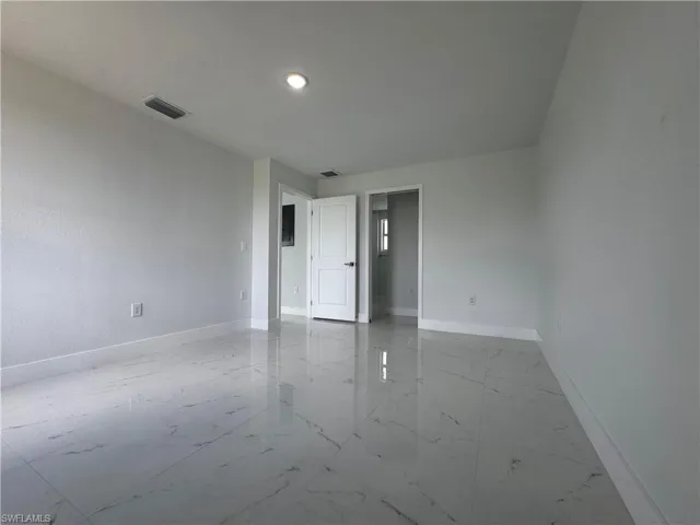 Empty room featuring light marble finish flooring and recessed lighting