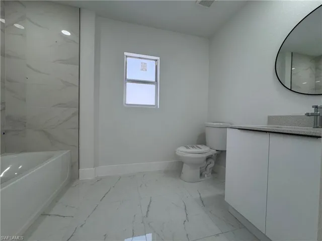Bathroom with vanity, light marble finish flooring, and a combined bath / shower with marble appearance