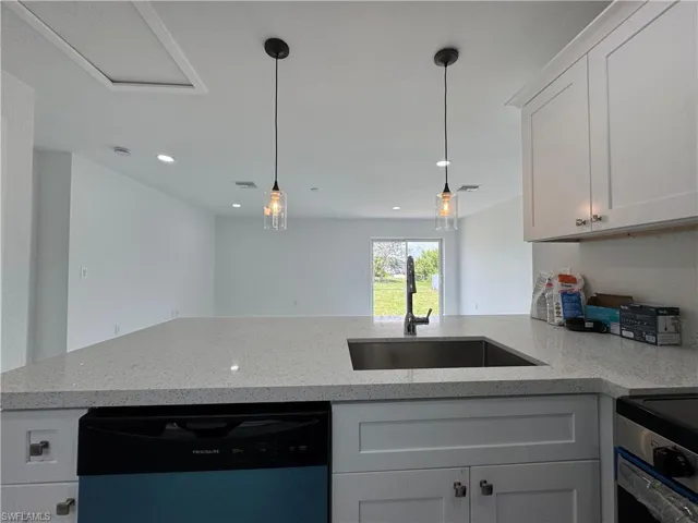 Kitchen featuring white cabinets, dishwasher, and light stone counters