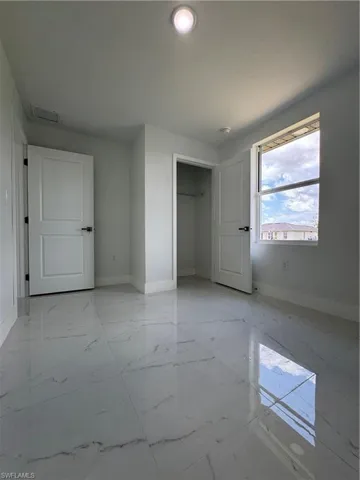 Unfurnished bedroom with a closet and light marble finish flooring