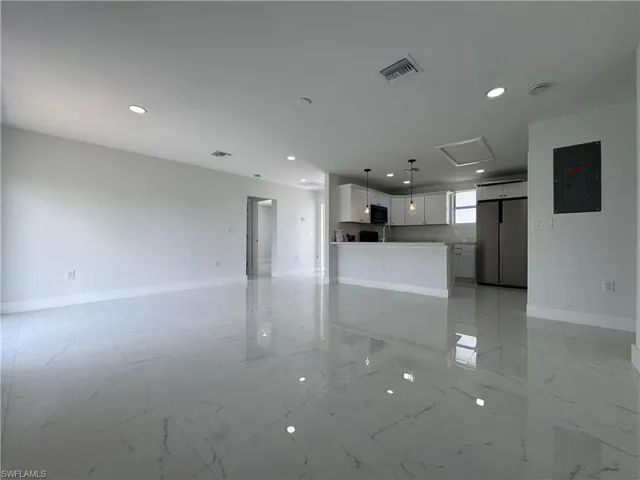 Unfurnished living room featuring electric panel, recessed lighting, and light marble finish flooring