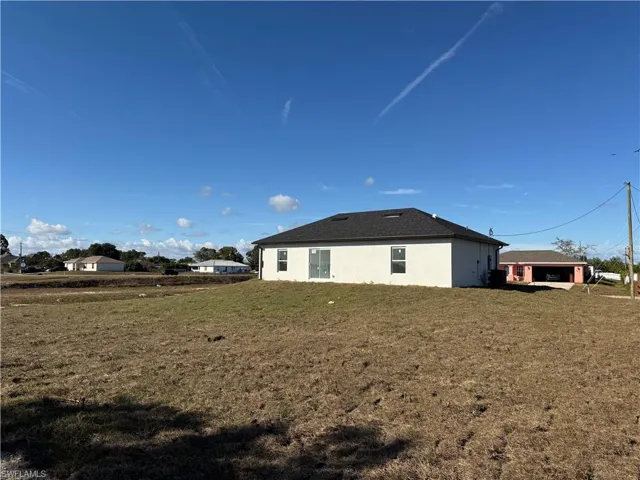 Rear view of house featuring stucco siding and a yard