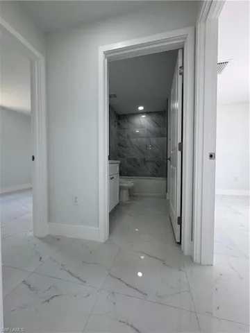 Corridor with baseboards and light marble finish flooring