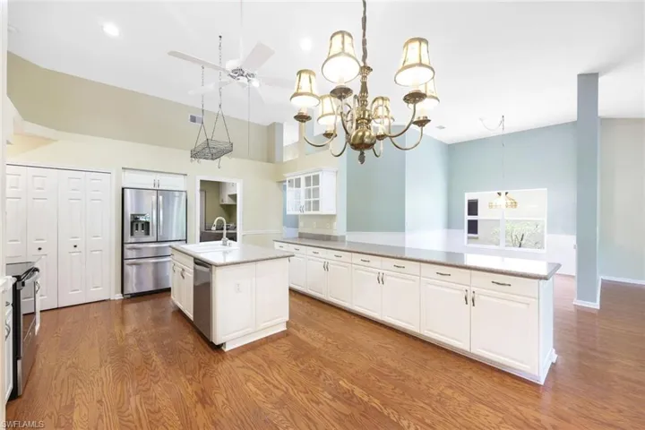 Kitchen with white cabinetry, an island with sink, appliances with stainless steel finishes, hardwood / wood-style floors, and sink