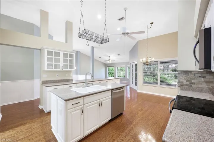 Kitchen with quartz counters, stainless steel kitchen appliances, a kitchen island with sink, white cabinetry
