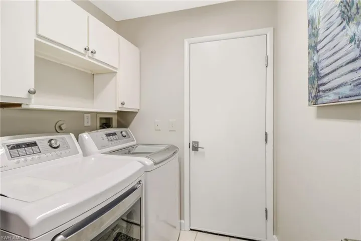 Laundry area with independent washer and dryer, cabinet space, and light tile patterned floors
