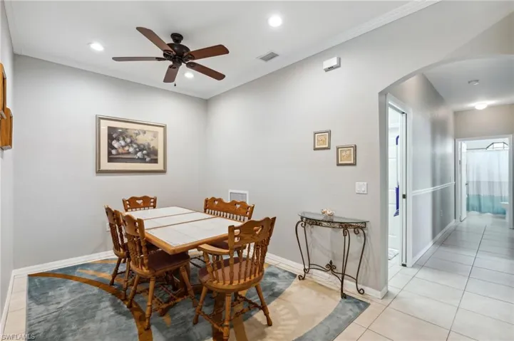 Tiled dining area with ceiling fan and crown molding