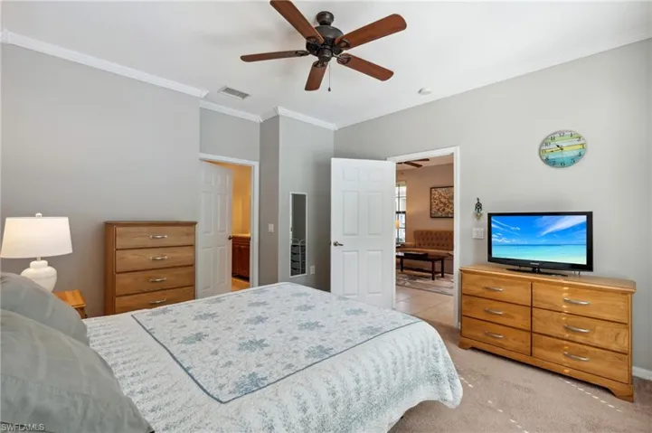 Bedroom featuring ceiling fan, light colored carpet, and crown molding