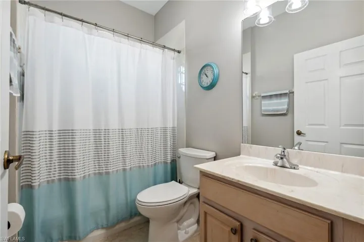 Bathroom featuring a shower with shower curtain, vanity, and toilet