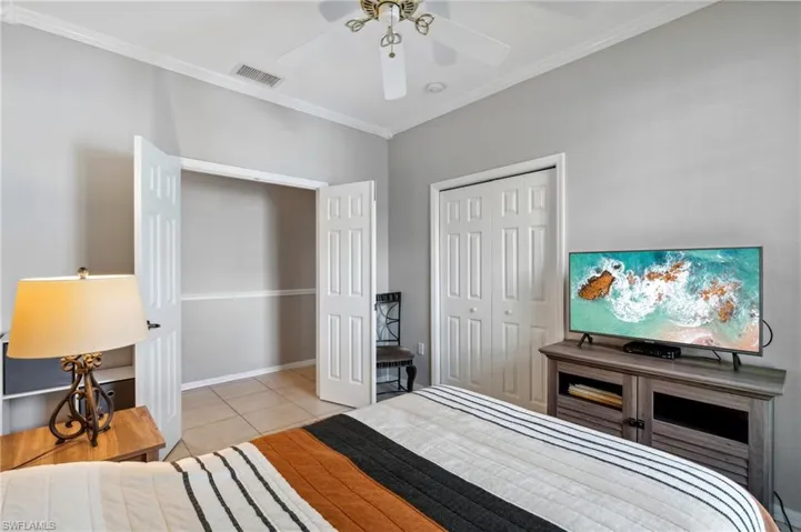 Bedroom featuring light tile patterned floors, a closet, ceiling fan, and crown molding