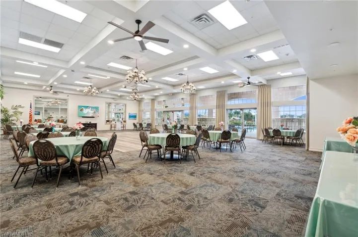 Carpeted dining room featuring ceiling fan with notable chandelier, beamed ceiling, and coffered ceiling