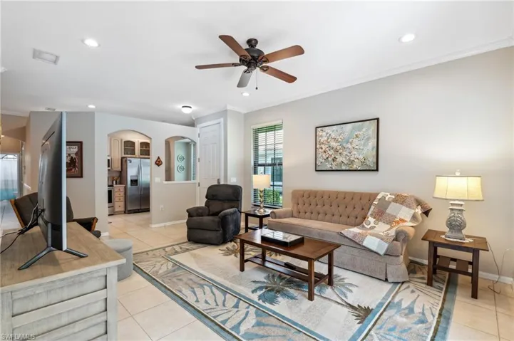 Tiled living room featuring ornamental molding and ceiling fan