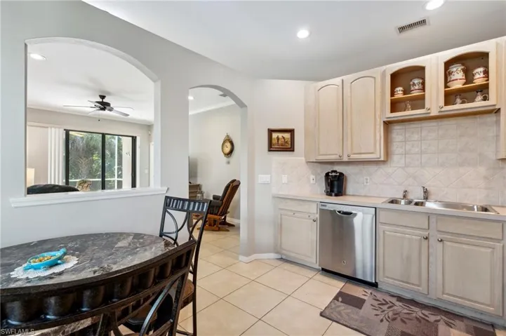 Kitchen with backsplash, light brown cabinets, dishwasher, light tile patterned floors, and sink