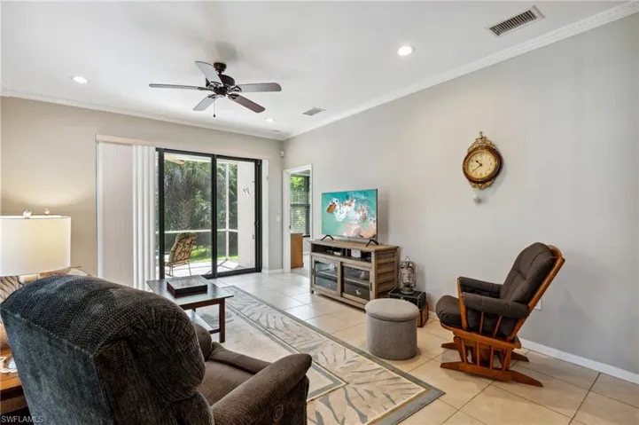 Living room with ceiling fan, crown molding, and light tile patterned floors