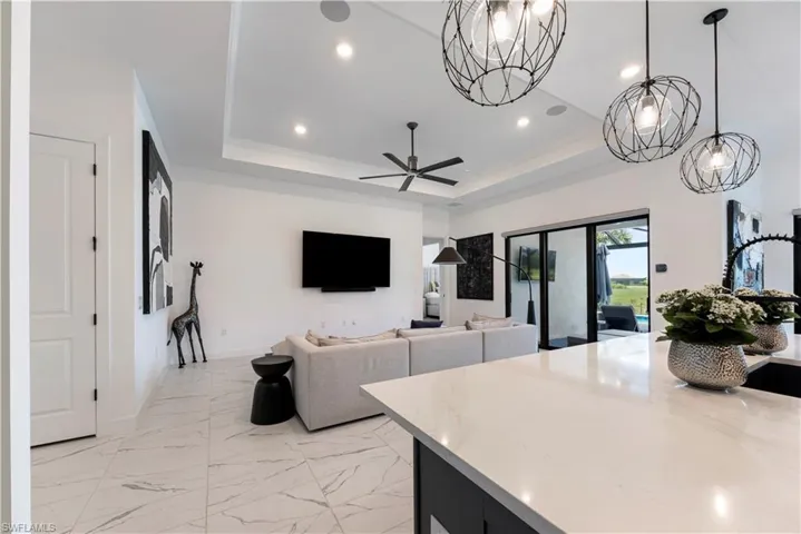 Spacious living area featuring high tray ceilings, recessed lighting, and large format tile flooring