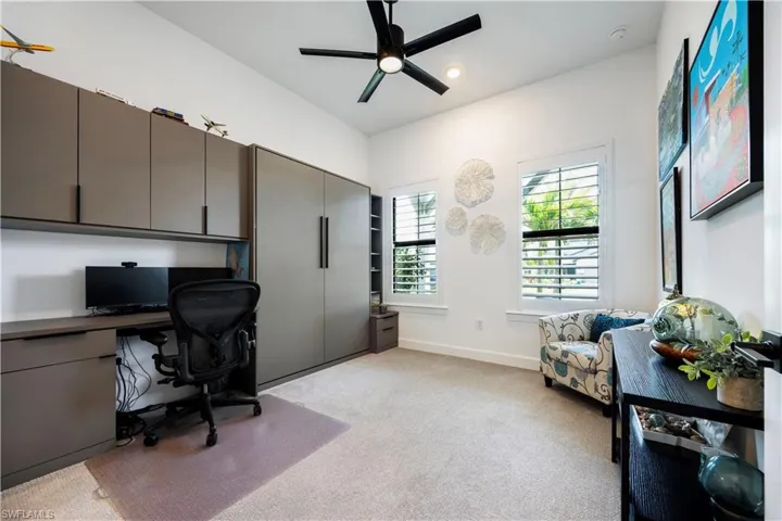 Integrated wall unit featuring a built-in desk, overhead cabinetry, and an enclosed storage system