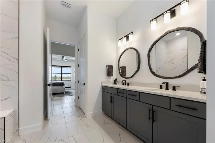 Dual vanity with dark cabinetry, white countertops, and black fixtures