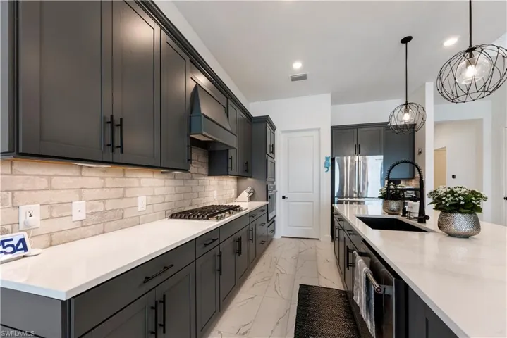 Gourmet kitchen featuring dark shaker-style cabinetry, white countertops, a light brick-patterned backsplash, and a black gooseneck faucet