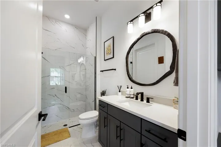 Contemporary bathroom featuring a dark vanity with a light countertop, a vessel sink, and a matte black faucet