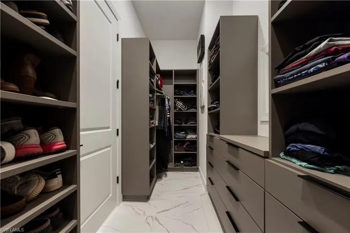 Custom closet system featuring extensive shelving, built-in drawer units, and a central walkway