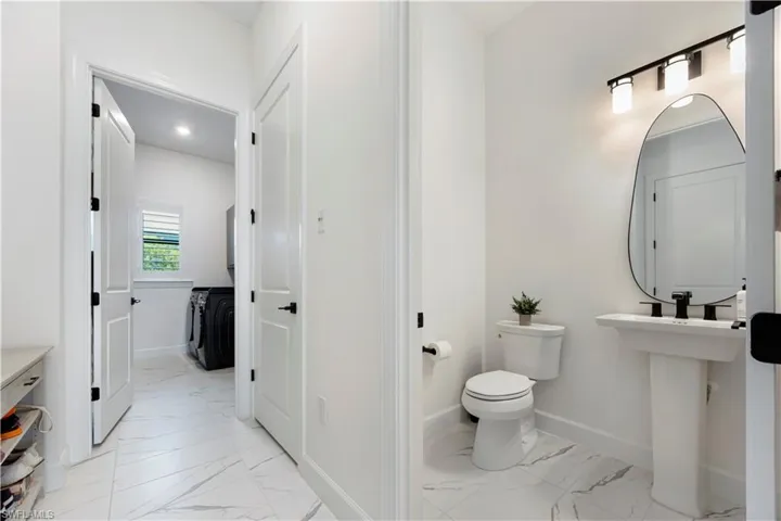 Modern bathroom featuring a pedestal sink, wall-mounted mirror, and black-finish hardware