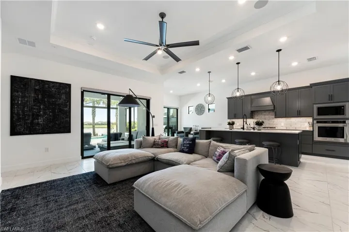 Open-concept living space with large format tile flooring and a tray ceiling