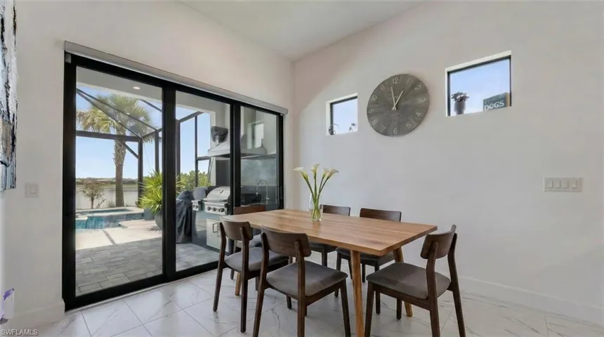 *Virtually Staged*Dining area featuring a vaulted ceiling, white walls, and white marble-look tile flooring