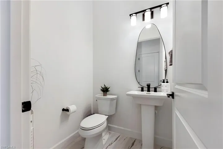 Powder room with a white pedestal sink, matte black faucet, and a contemporary frameless mirror