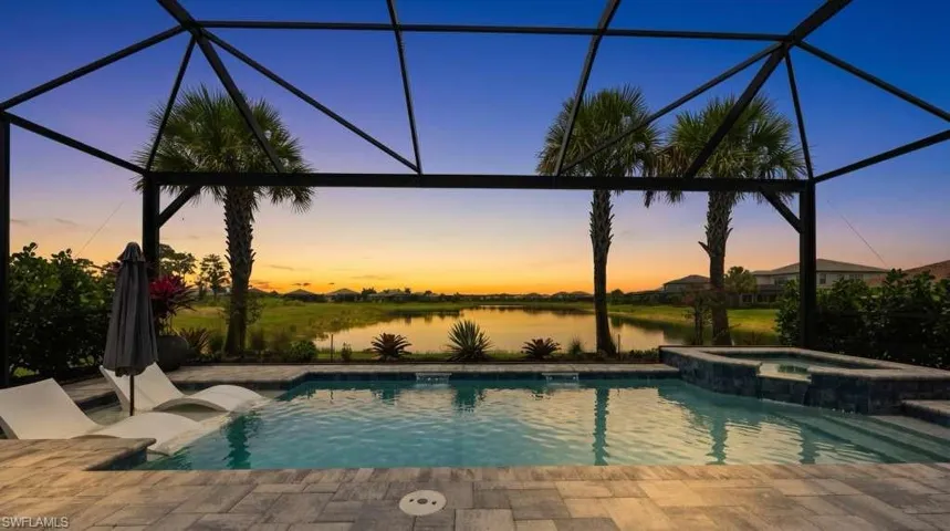 Screened lanai featuring a swimming pool, integrated spa, and expansive paver decking