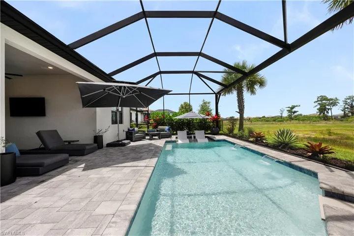 Screened lanai with rectangular swimming pool featuring multiple water jets and integrated steps