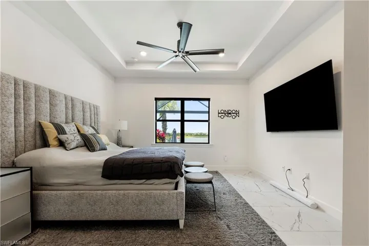 Bedroom featuring a tray ceiling with recessed lighting and a ceiling fan
