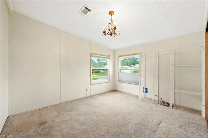 Unfurnished bedroom featuring carpet floors, a closet, a textured ceiling, and a chandelier
