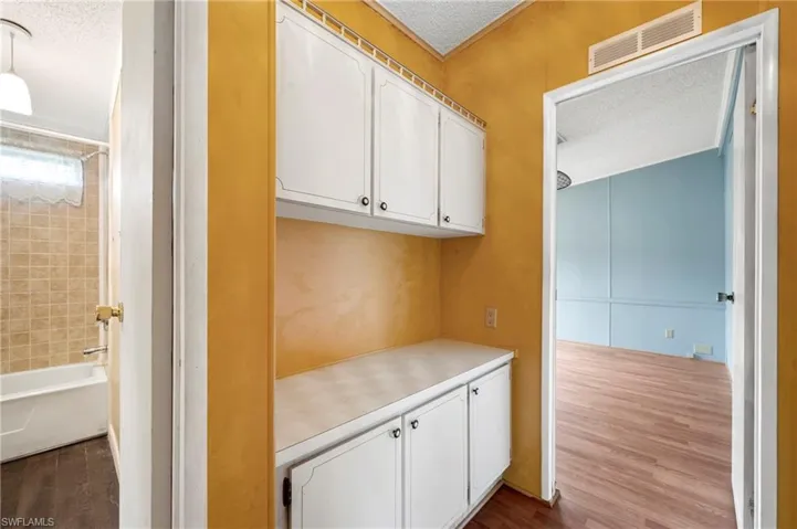 Kitchen featuring white cabinets, light countertops, dark wood-type flooring, and a textured ceiling