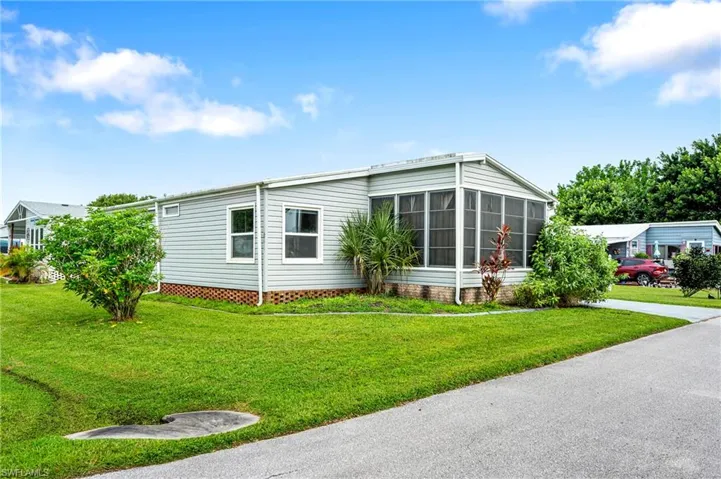 View of property exterior with a lawn and a sunroom