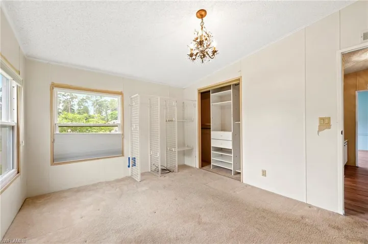 Unfurnished bedroom featuring carpet floors, a closet, a textured ceiling, and a chandelier