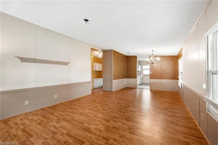 Family room featuring light wood-style floors, a chandelier, a textured ceiling, and a decorative wall