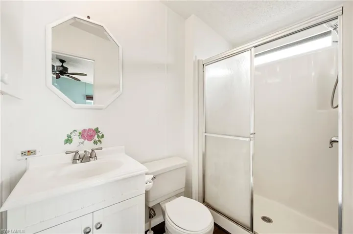 Full bathroom with vanity, a shower stall, a textured ceiling, and ceiling fan
