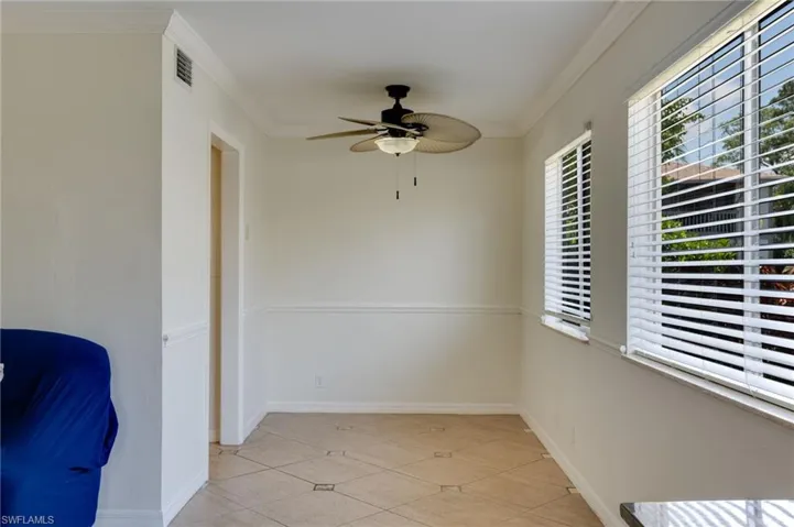 Room featuring a ceiling fan with integrated lighting, crown molding, and wainscoting